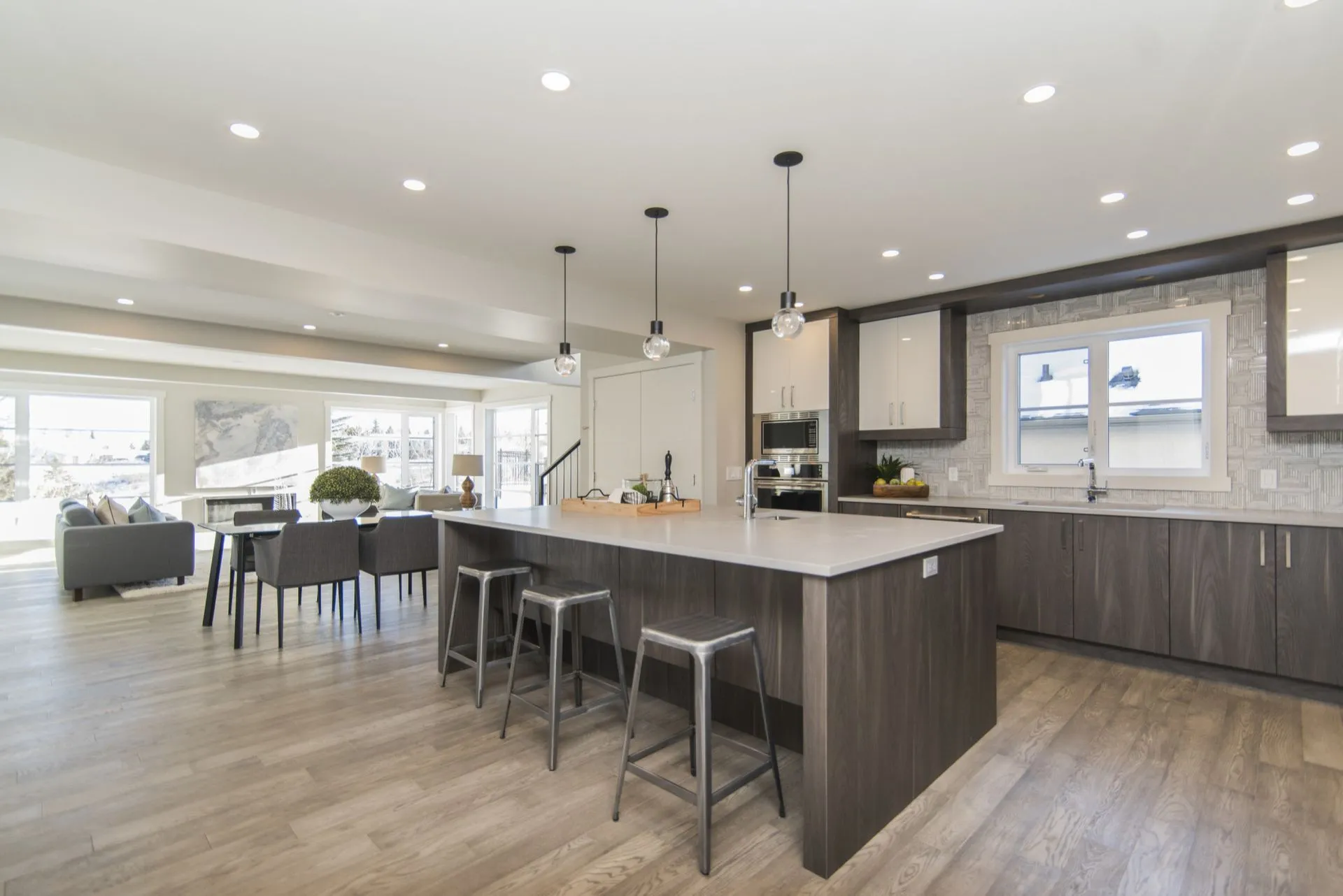 Bright modern kitchen with a large island, bar stools, and an open dining and living area
