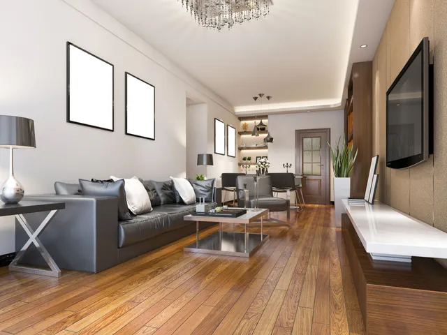 Modern living room with gray sofa, wooden floors, wall-mounted TV, and open shelving in the back.
