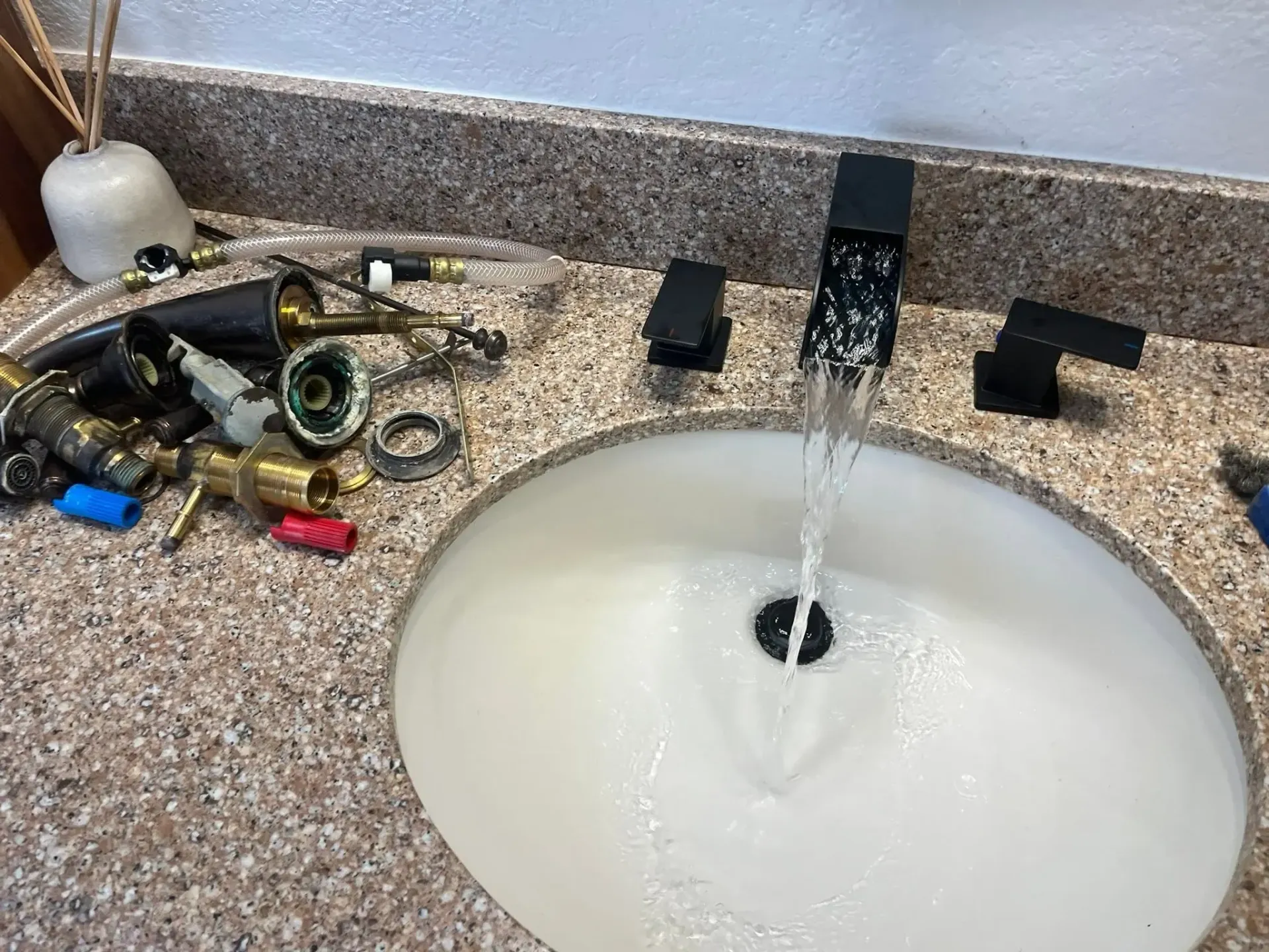 Bathroom sink with running faucet, soap dispenser, and scattered tools on the counter